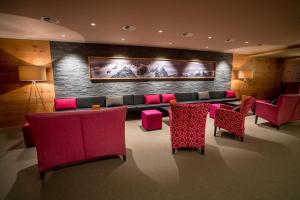 a living room with a couch and red chairs at Hotel Panorama in Hasliberg