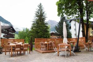 a patio with tables and chairs and an umbrella at GH Hotel Piaz in Pozza di Fassa