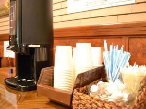 een tafel met een mand met borden en kopjes en een koffiezetapparaat bij Hotel Crown Hills Koriyama in Koriyama