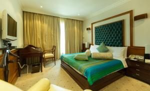 a hotel room with a bed and a desk and a piano at The Chancery Pavilion in Bangalore