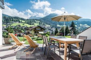 een houten tafel met stoelen en een parasol op een patio bij Chalet Sophia in Ortisei