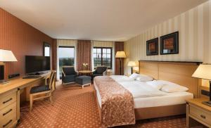 a hotel room with a bed and a desk and a television at Maritim Hotel Dresden in Dresden