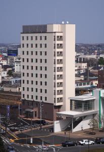 een groot wit gebouw met een parkeerplaats ervoor bij Life Inn Katsuta Station West in Hitachinaka