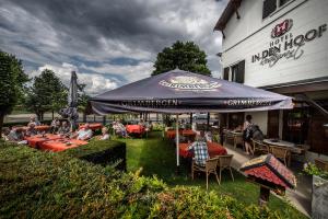 Un groupe de personnes assis à table sous un parapluie dans l'établissement Hotel Restaurant in den Hoof, à Maastricht