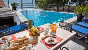 - une table avec de la nourriture et des boissons à côté de la piscine dans l'établissement Villa Marina, à Omiš