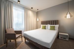 ein Schlafzimmer mit einem großen weißen Bett und einem Stuhl in der Unterkunft ibis Styles Siedlce in Siedlce