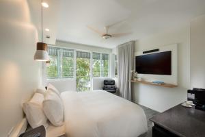 1 dormitorio blanco con 1 cama y TV en Heart Hotel and Gallery Whitsundays, en Airlie Beach