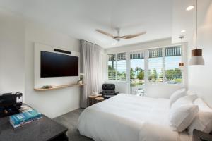 1 dormitorio blanco con 1 cama grande y TV en Heart Hotel and Gallery Whitsundays, en Airlie Beach