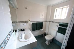 a white bathroom with a sink and a toilet at Abel Tasman Motor Inn in Dubbo