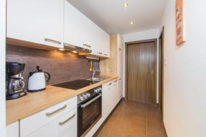 a kitchen with white cabinets and a stove top oven at Apart Alpen in Längenfeld