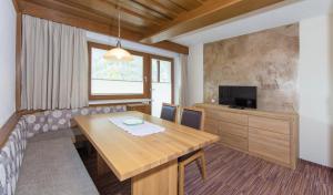 a dining room with a table and a television at Apart Alpen in Längenfeld