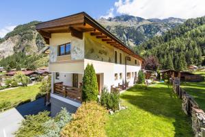 a house on a hill with mountains in the background at Apart Alpen in Längenfeld