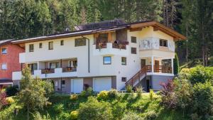 a large white building on a hill with trees at Apart Alpen in Längenfeld