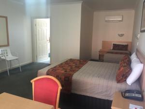 a hotel room with a bed and a table and chair at Abel Tasman Motor Inn in Dubbo