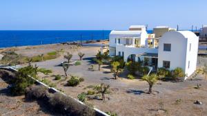 een wit gebouw met bomen voor de oceaan bij Sun Anemos Resort in Oia