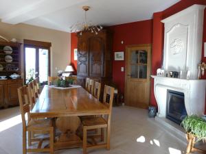 a dining room with a wooden table and a fireplace at L'orchidée in Rochehaut