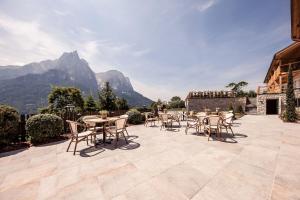 un patio con tavoli e sedie con montagne sullo sfondo di Sonus Alpis - Adults Only a Castelrotto