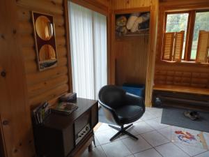 una silla negra en una sala con chimenea en Chalet Saint-Thomas, en L'Anse-Saint-Jean