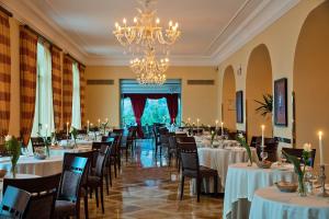 un comedor con mesas y sillas y una lámpara de araña en Grand Hotel Due Golfi, en SantʼAgata sui Due Golfi