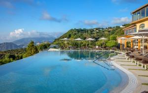 una gran piscina con sillas y sombrillas en Grand Hotel Due Golfi, en SantʼAgata sui Due Golfi