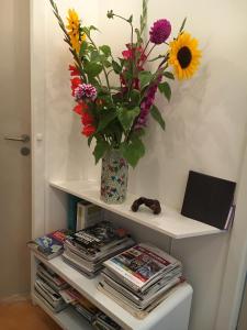 a shelf with a vase with flowers and magazines at Helts B&B - Helts Guesthouse in Herning