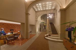 eine Lobby mit einer Treppe und eine Person am Tisch in der Unterkunft H10 Casa Mimosa 4* Sup in Barcelona