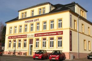 dois carros estacionados em frente a um edifício amarelo em Pension Luft em Dresden