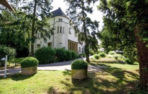 una grande casa bianca con alberi di fronte di Hofgut Dippelshof Hotel- und Restaurant KG a Darmstadt