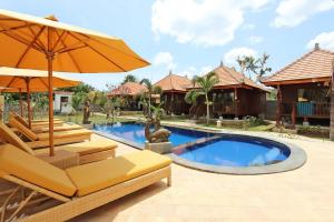 una piscina con sillas y una sombrilla junto a una casa en Dream Beach Cottages, en Nusa Lembongan