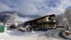 un bâtiment dans la neige avec des voitures garées devant dans l'établissement Hotel Dorfgasthof Schlösslstube, à Stuhlfelden