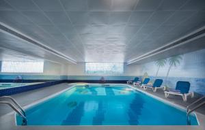 une grande piscine avec des chaises bleues dans un bâtiment dans l'établissement Admiral Plaza Hotel, à Dubaï