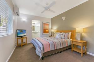 a bedroom with a bed and a television in it at Bali Hai Apartments Noosa in Noosa Heads