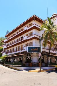 een groot gebouw met een palmboom ervoor bij Olas Altas Suites Departamentos in Puerto Vallarta