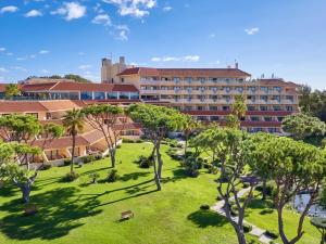 un complexe avec une pelouse et des arbres devant un bâtiment dans l'établissement Hotel Quinta do Lago, à Quinta do Lago