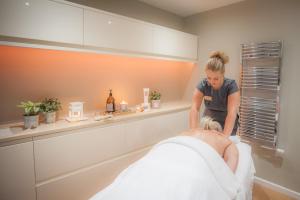 une femme qui donne un massage à un homme dans un salon dans l'établissement Woodbury Park Hotel & Spa, à Exeter