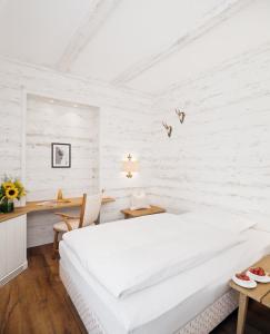 a white bedroom with a large bed and a desk at Eden Hotel Wolff in Munich