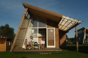 une femme et deux enfants assis à une table devant une maison dans l'établissement Dancamps Kolding City, à Kolding