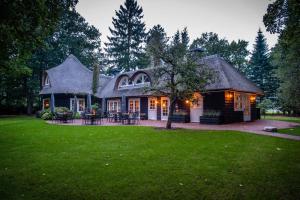 une maison avec une pelouse verte devant elle dans l'établissement Van der Valk Hotel Apeldoorn - de Cantharel, à Apeldoorn