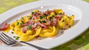 un piatto di cibo con pasta con prosciutto e formaggio di Hotel Moritz a Dobbiaco