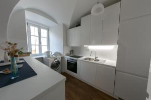 a white kitchen with white cabinets and a sink at 3 Bridges App in Ljubljana