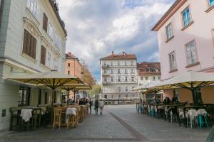 a group of tables and chairs with umbrellas on a street at 3 Bridges App in Ljubljana