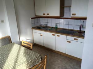 a kitchen with white cabinets and a table and a sink at Fallerhof in Villnoss