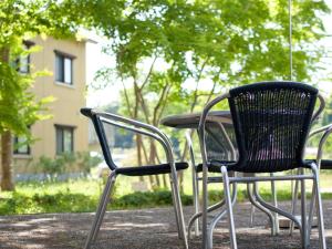 2 chaises et une table avec un parasol dans l'établissement Hotel Folkloro Hanamakitowa, à Hanamaki