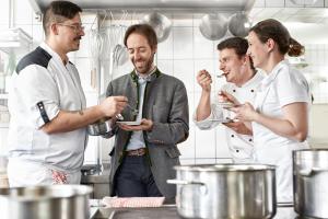 eine Gruppe von Menschen, die in einer Küche stehen und Essen zubereiten in der Unterkunft Hotel Gasthof Krone in Hittisau