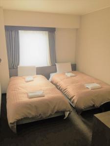 - 2 lits dans une chambre avec fenêtre dans l'établissement Hotel Crown Hills Yamagata, à Yamagata