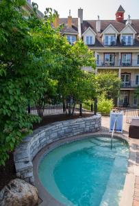 einen Pool in einem Garten mit einer steinernen Mauer in der Unterkunft Tour des Voyageurs in Mont-Tremblant