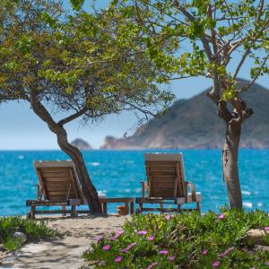 duas cadeiras sentadas na praia perto da água em Yonca Lodge em Fethiye