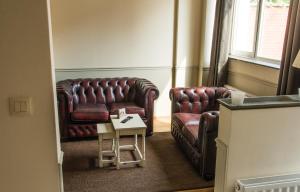 a living room with two leather chairs and a table at Hotel Saint Georges in Mons