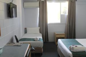 um pequeno quarto com 2 camas e uma televisão em Rocky Glen Hotel Motel Gladstone em Gladstone