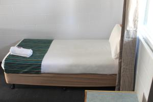 uma pequena cama num pequeno quarto com em Rocky Glen Hotel Motel Gladstone em Gladstone